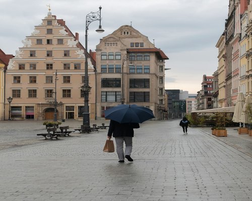 A person walking comfortably on a sidewalk in Wrocław during a cloudy afternoon